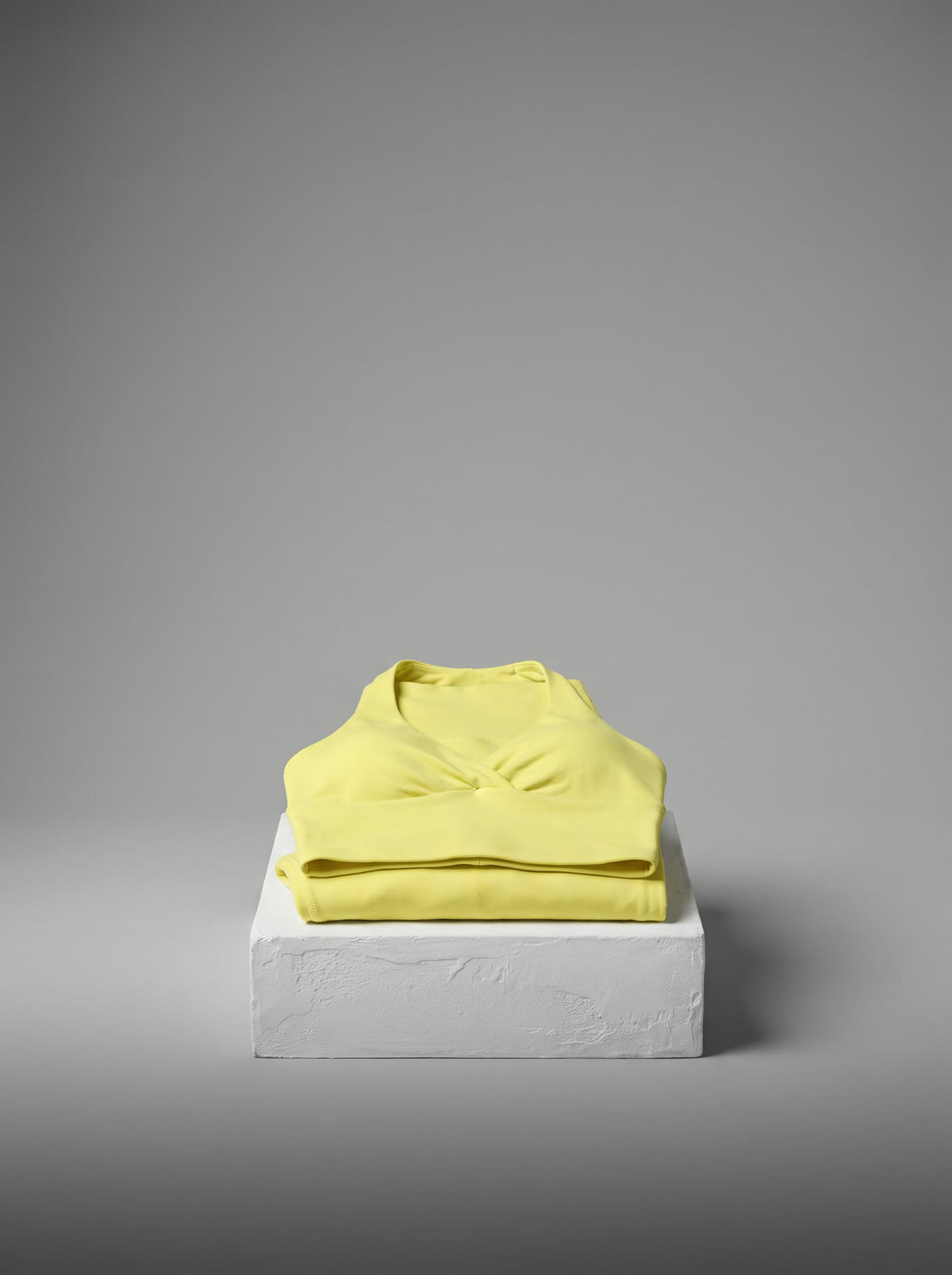 Yellow Pilates set folded on a white plinth